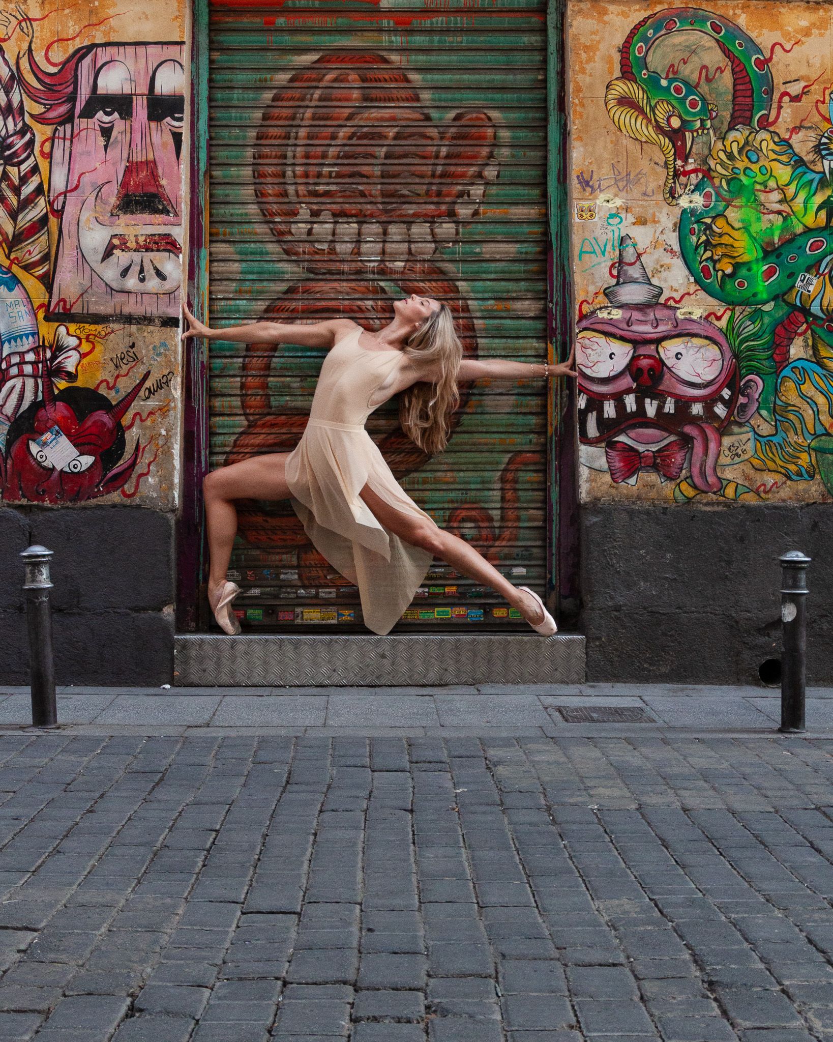 Dancer Cassandra Orefice in an en pointe pose in front of colourful murals in Malasana