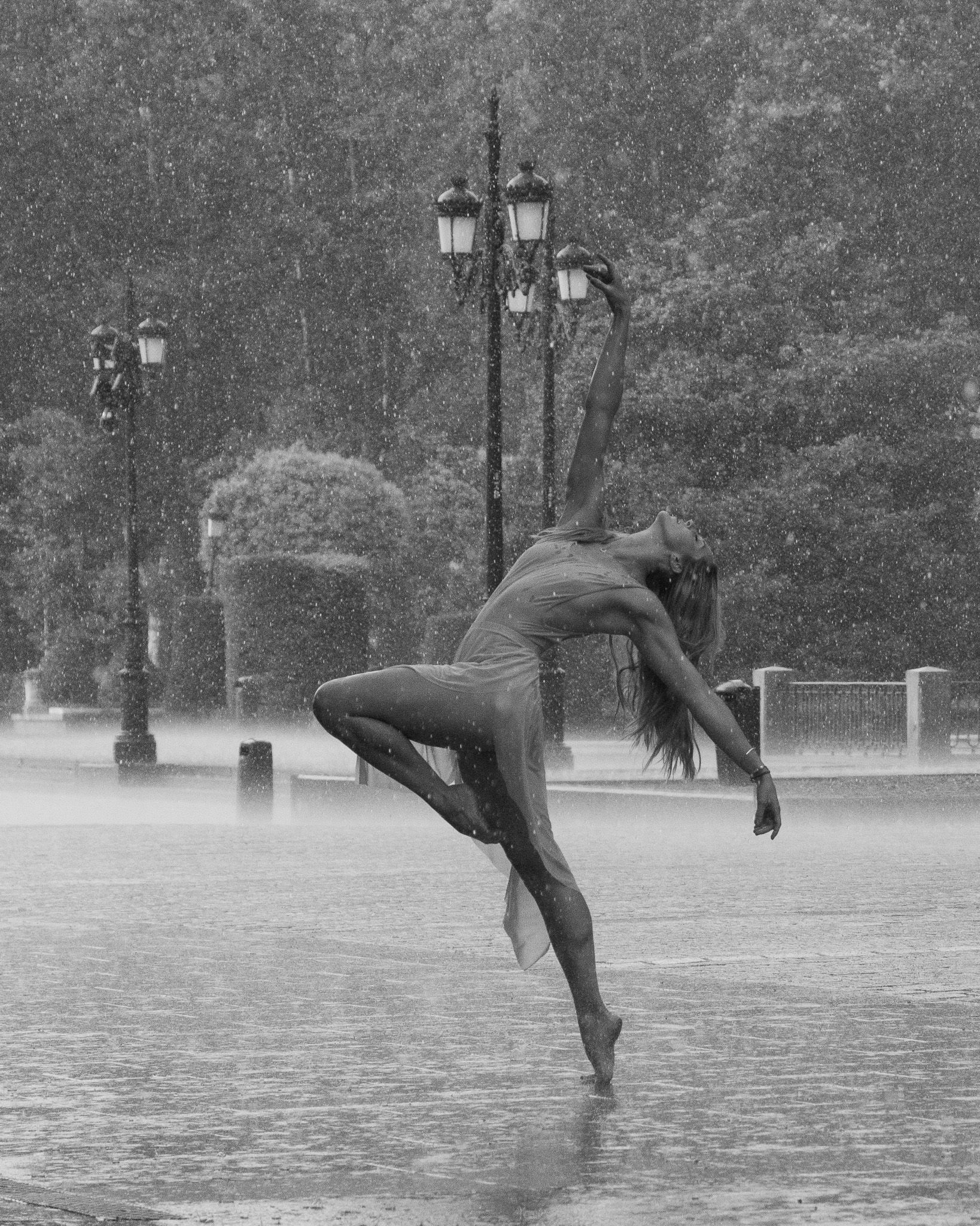 Dancer Cassandra Orefice arching backwards in the rain beside the Royal Palace of Madrid