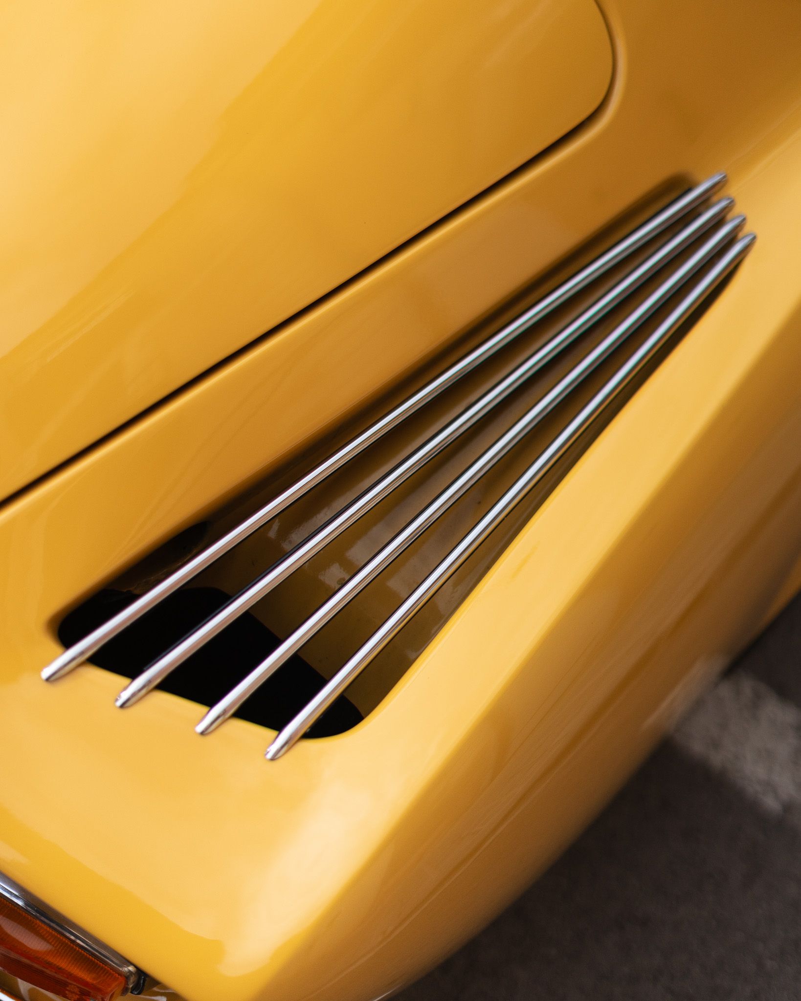 Detail of the hood and louvres of a yellow Alpine A110 in a luminous close-up