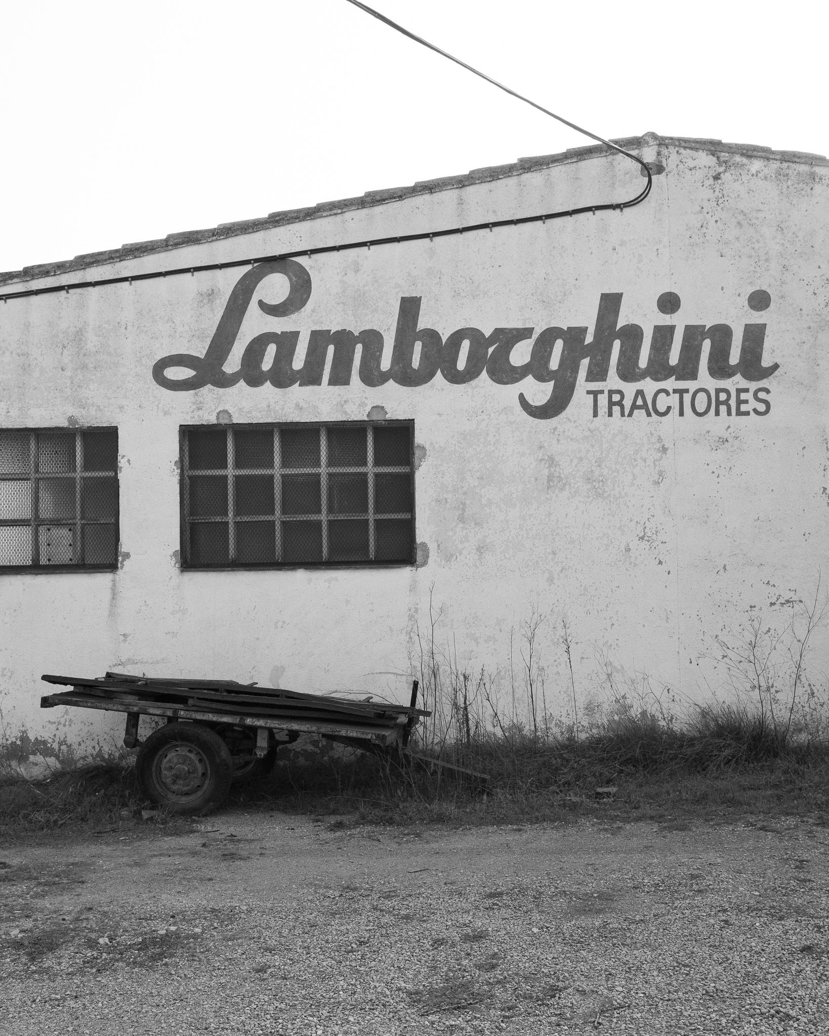 Abandoned facade with original Lamborghini Tractors sign and disused trailer