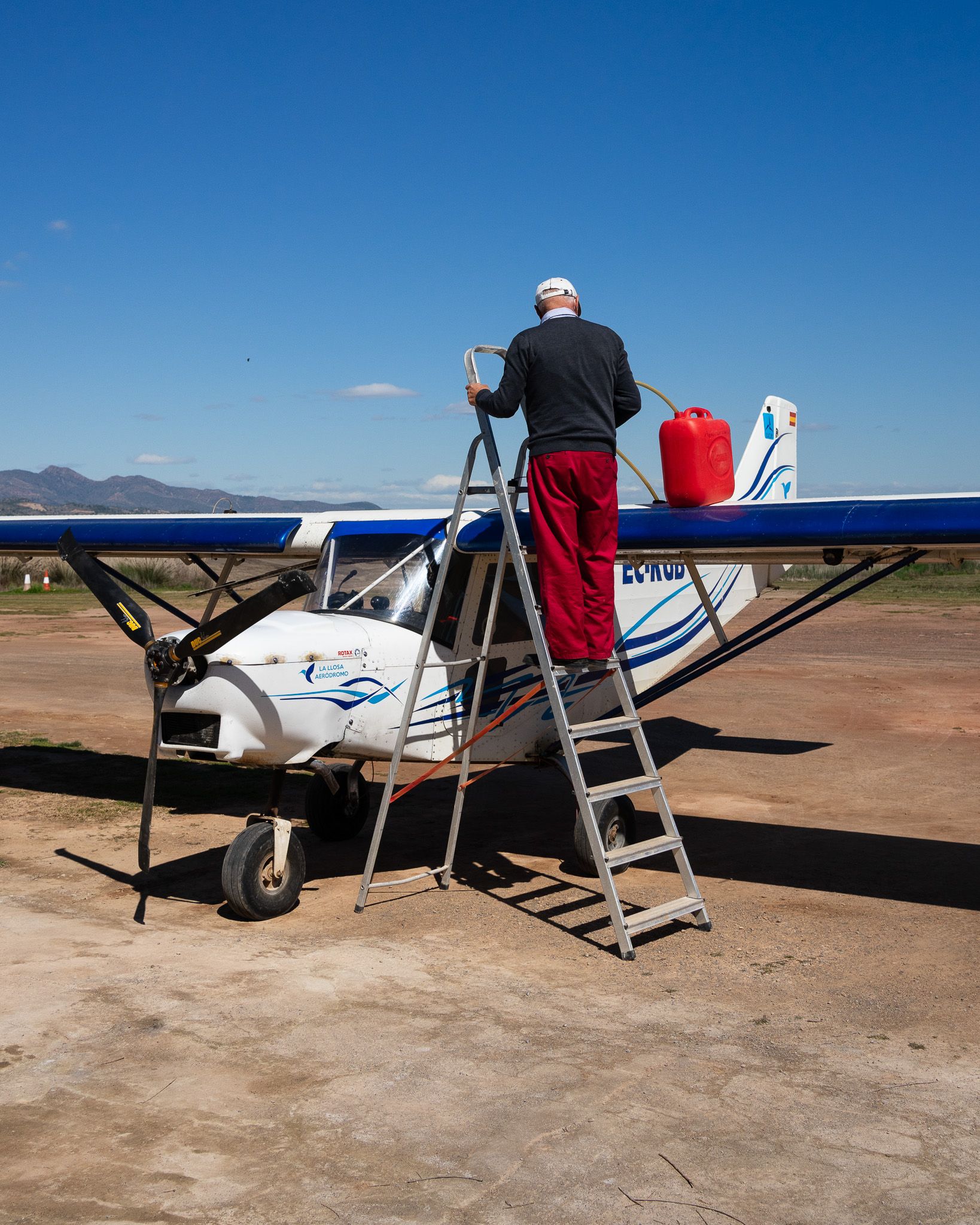 Pilot refuelling an ultralight with a red jerrycan at a Valencia airfield
