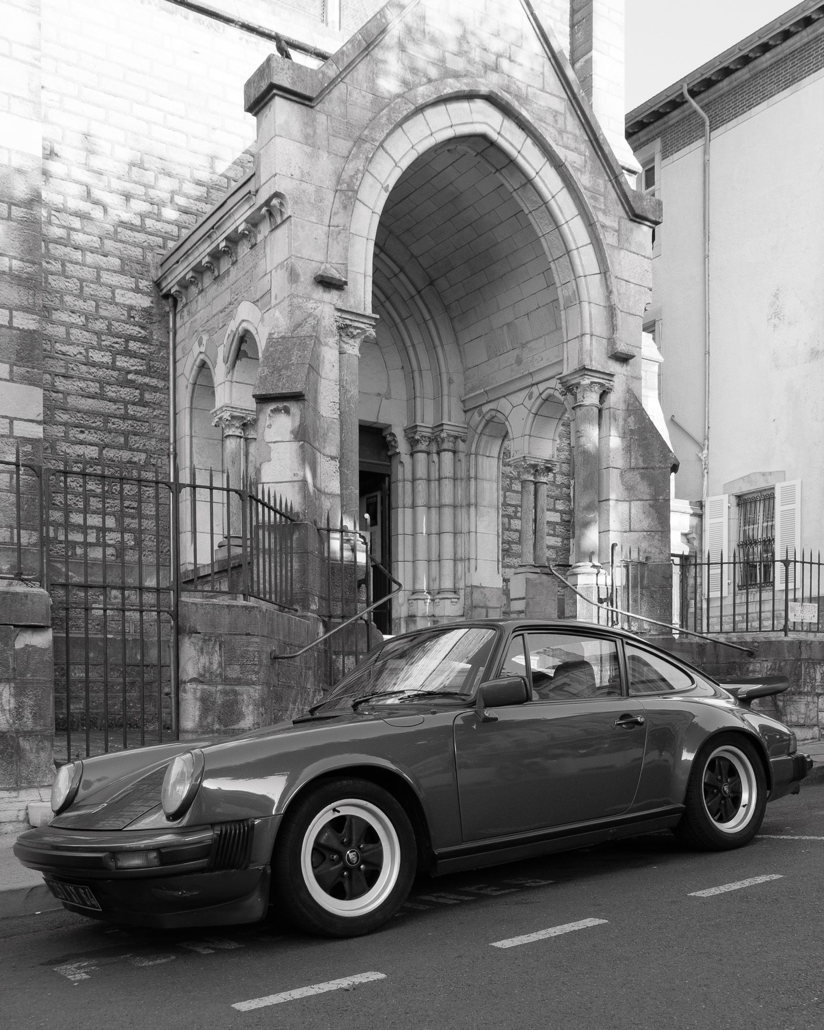 Classic Porsche parked in front of a stone church with arches in Biarritz