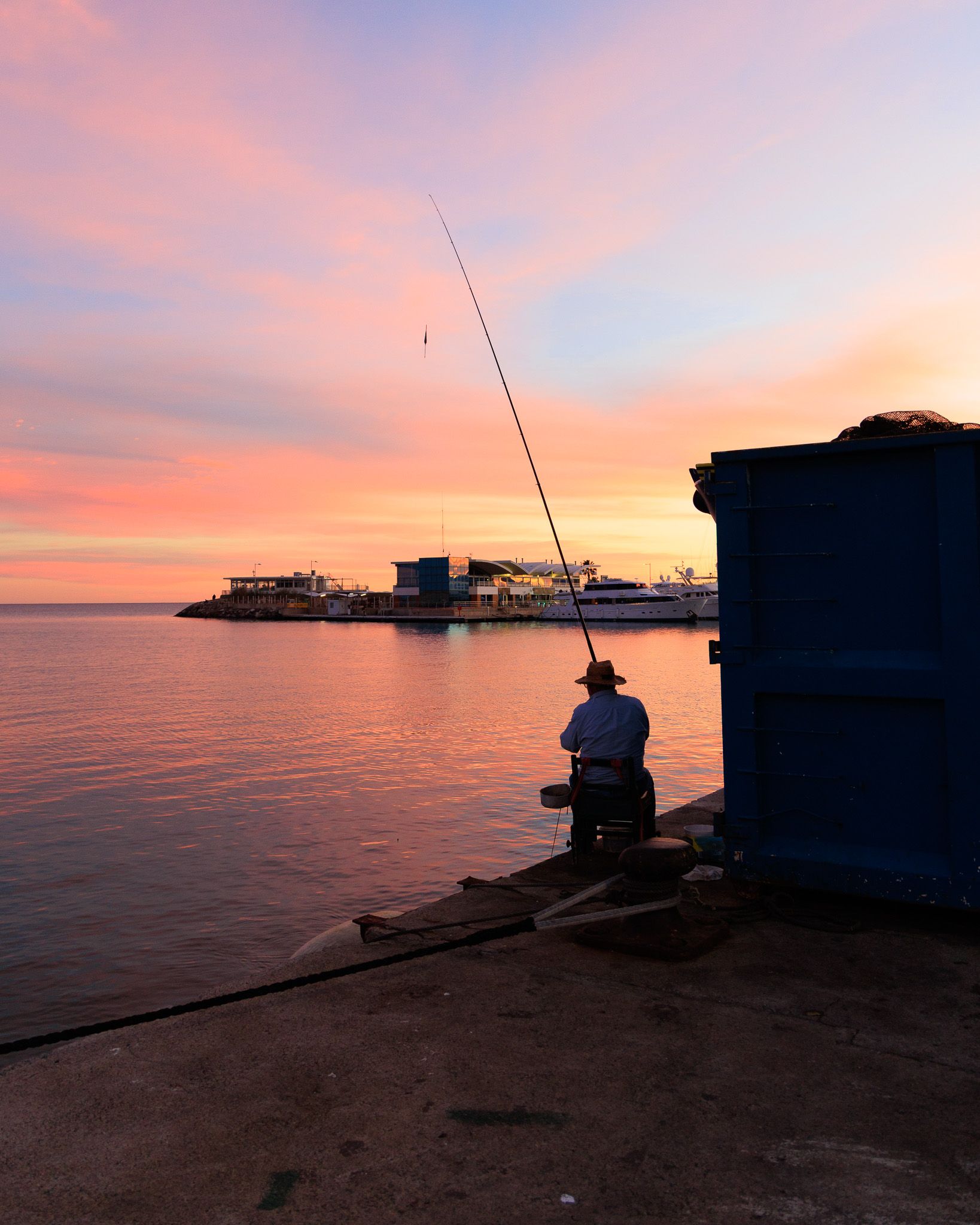 Man fishing at sunset on the pier of the port of Burriana, Castellón