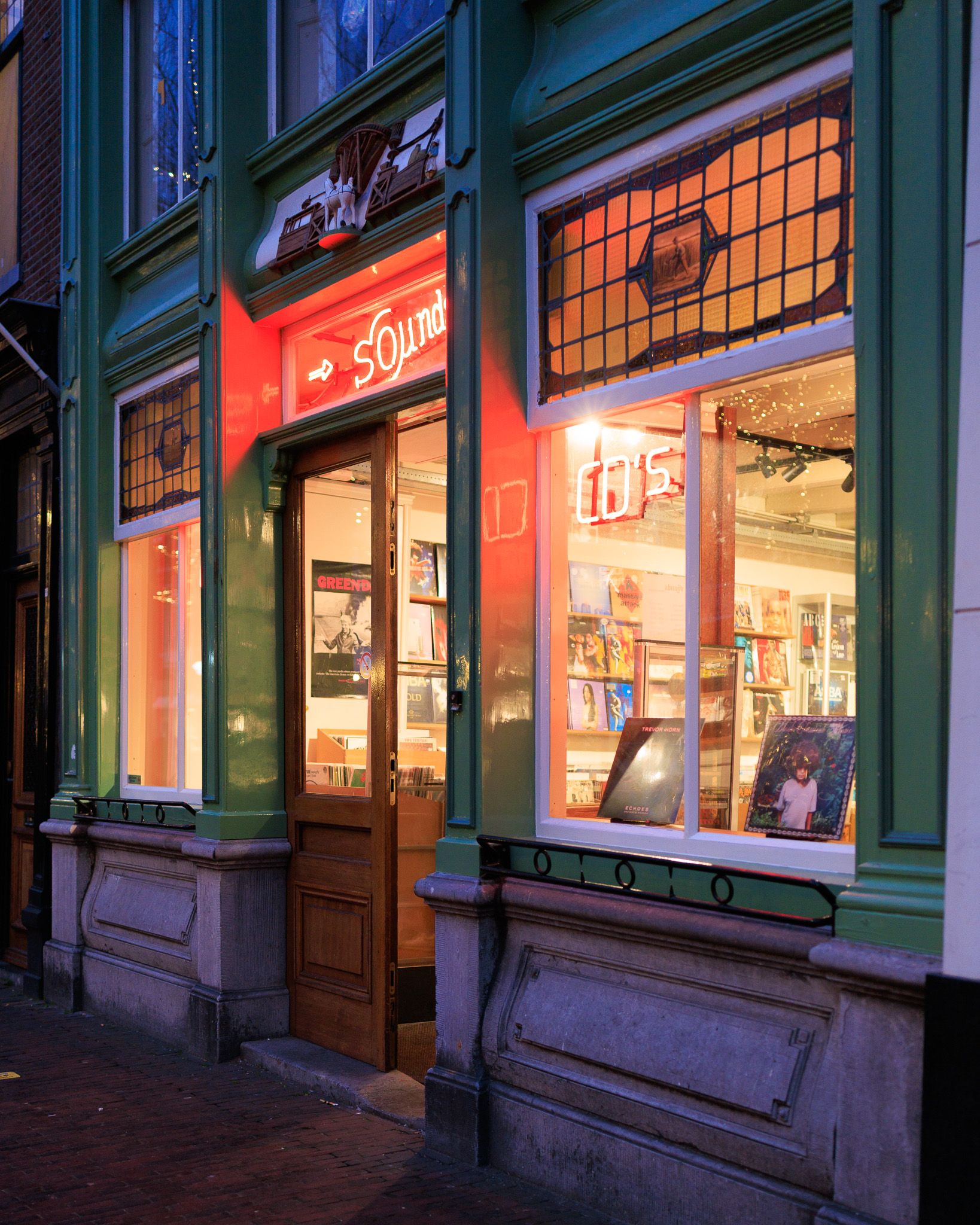 Facade of the Sounds record shop in Delft with red neon sign and vinyl records in the window