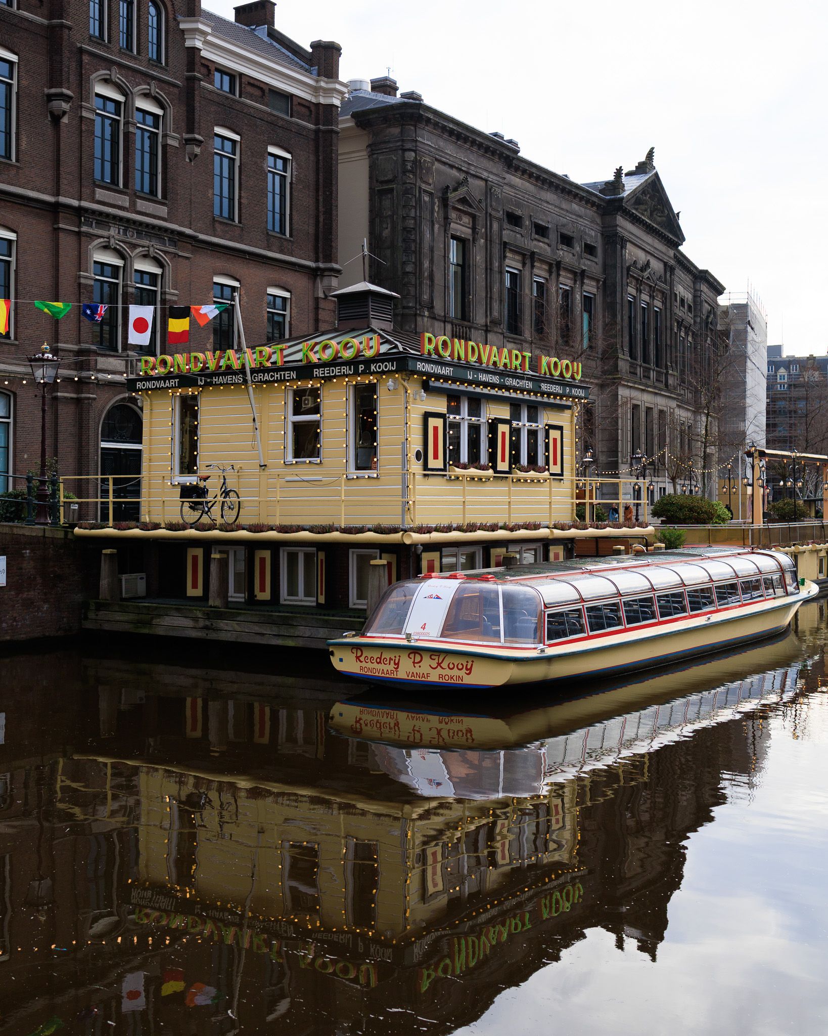 Rondvaart Kooij boat moored on an Amsterdam canal with reflections on the water