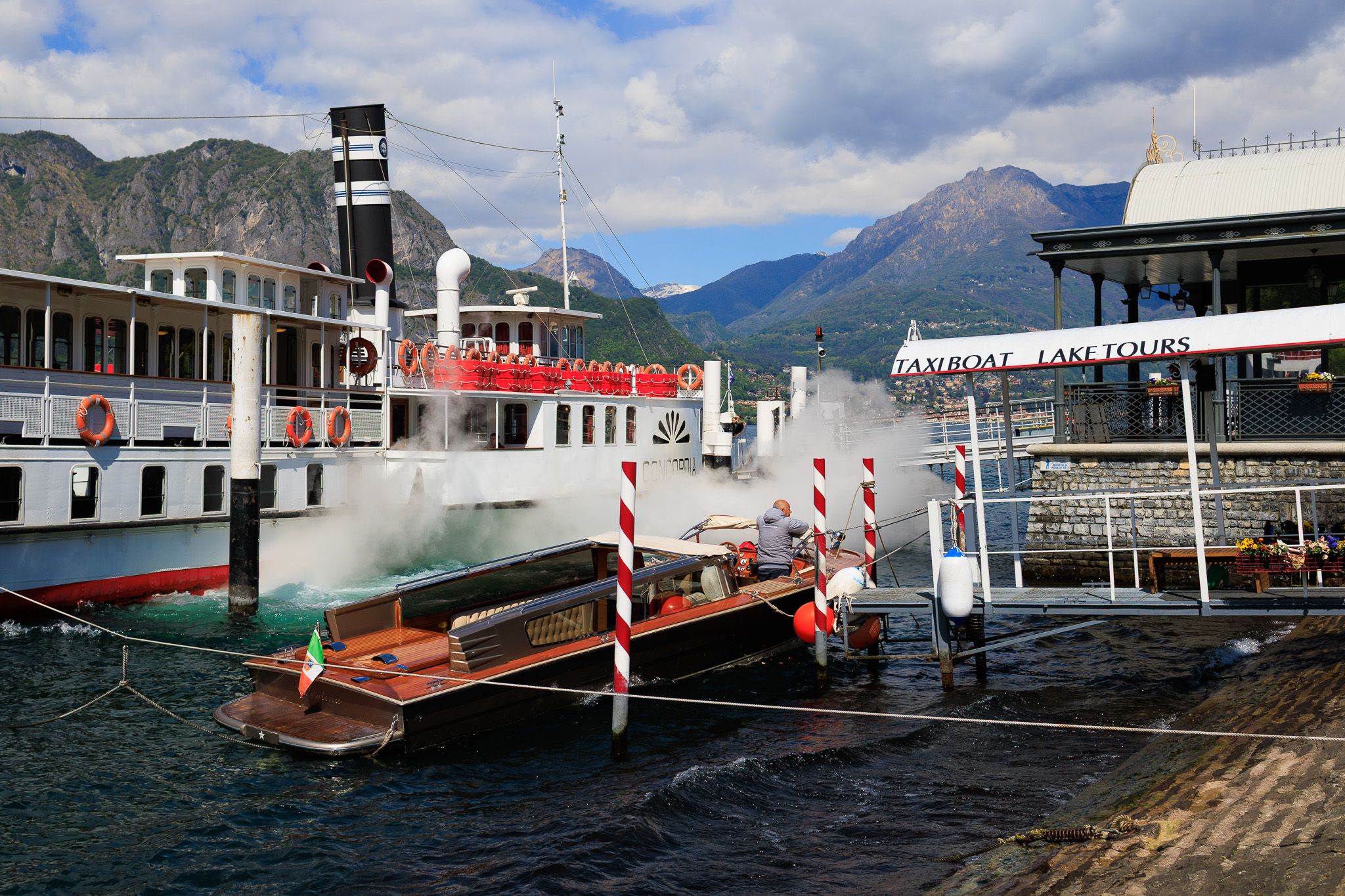 Steamboat and wooden taxi boat with Italian flag at the Bellagio pier