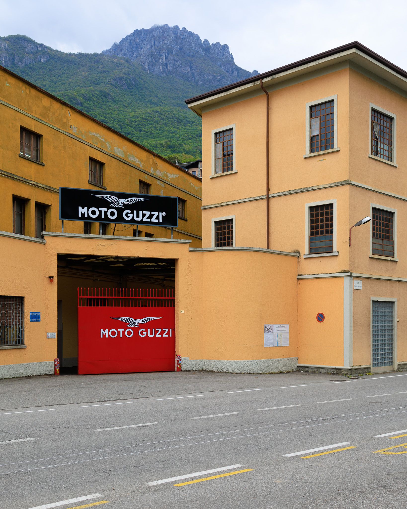 Entrance to the Moto Guzzi Museum with red gate and winged logo in Mandello del Lario