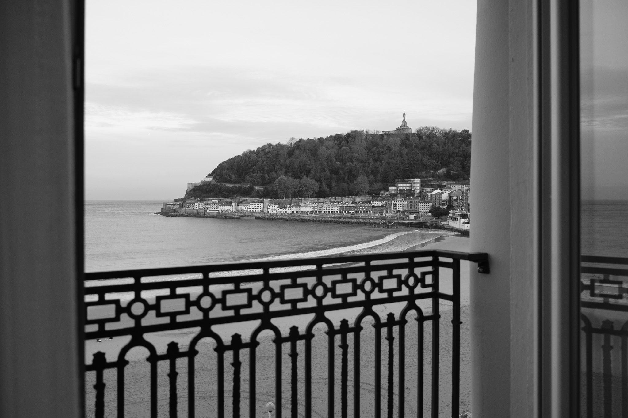 Sunrise over La Concha in black and white framed by the wrought-iron balcony of the Hotel de Londres